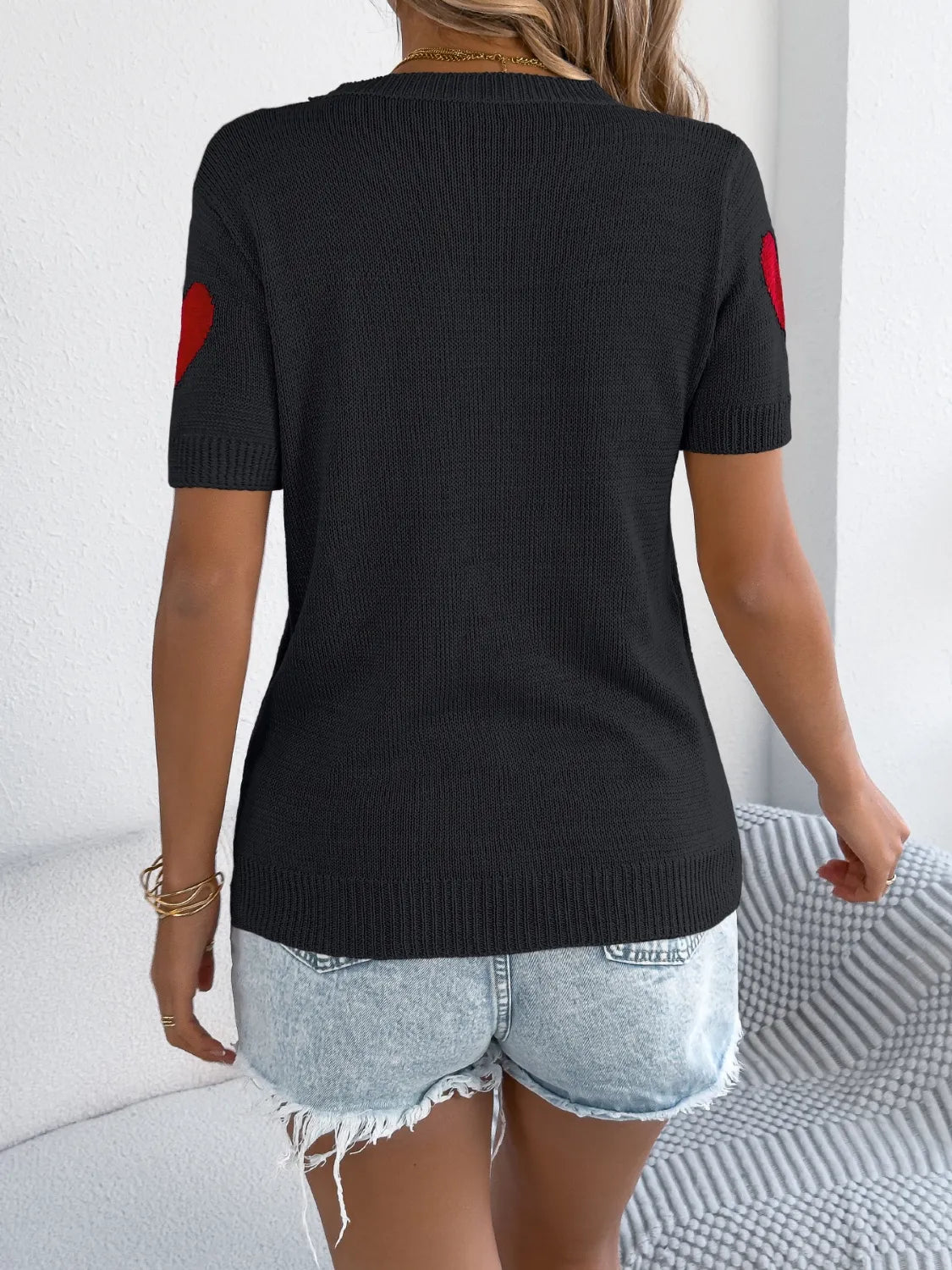 Black knit t-shirt with red heart detail on sleeves.