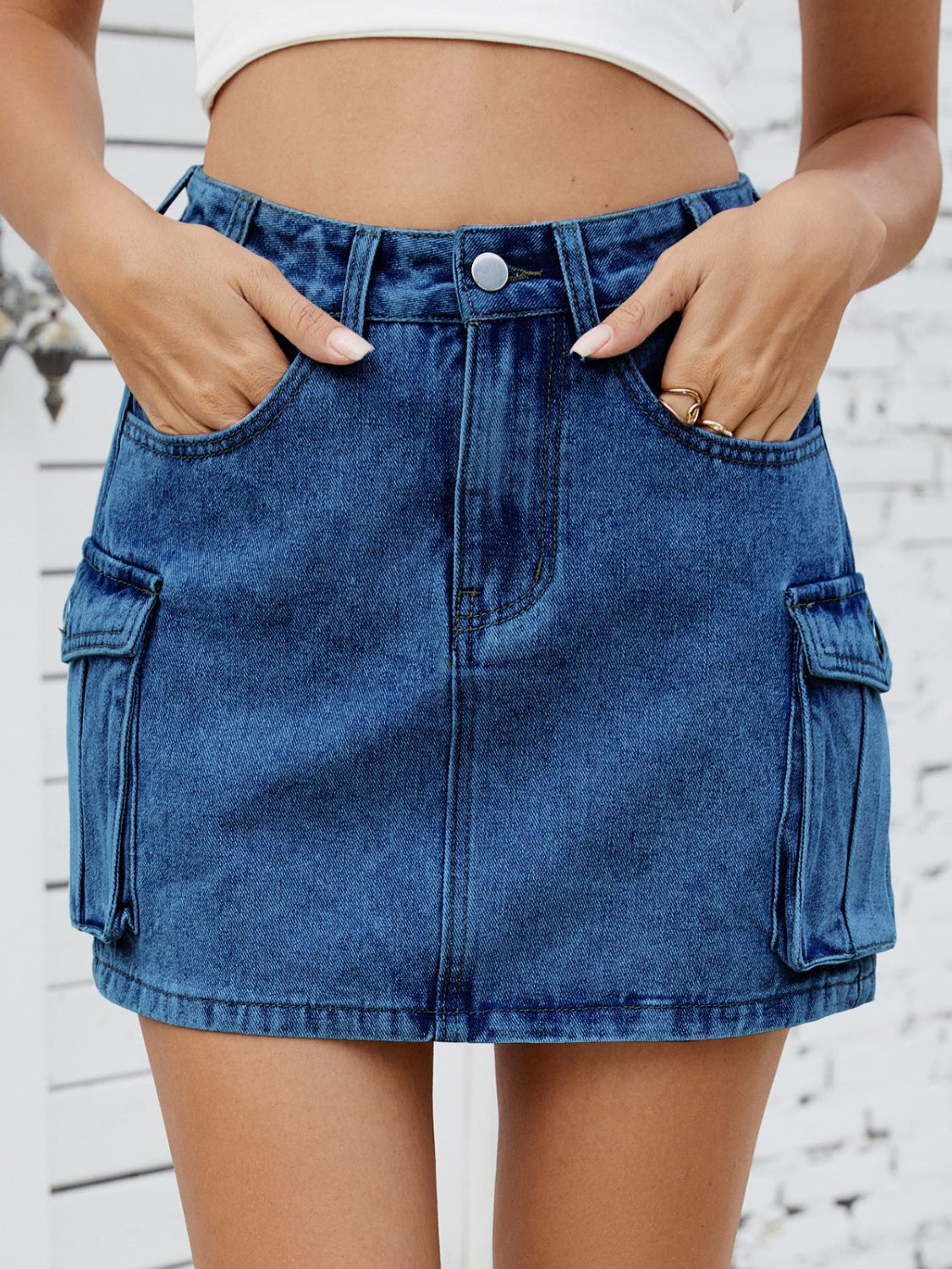 Medium wash denim mini skirt with cargo pockets and a button fly.