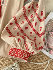 Khaki tie neck shirt with red folk embroidery on sleeves and cuffs.
