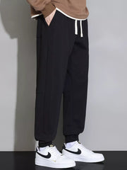 Black cuffed jogger pants with drawstring waist and pockets, styled with a brown hoodie.