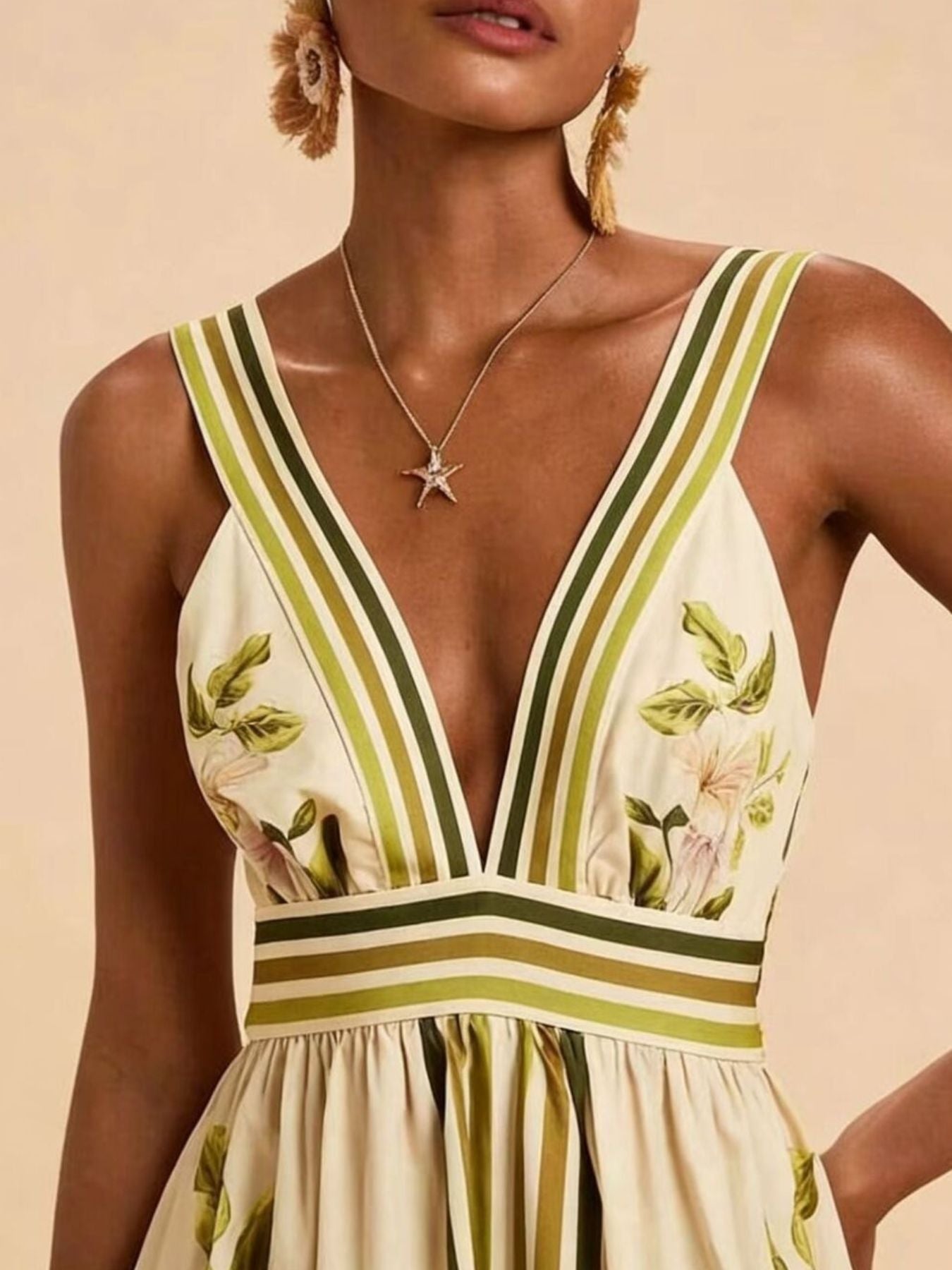 Tropical leaf print maxi dress with deep V-neck, striped straps, and empire waist.