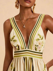 Tropical leaf print maxi dress with deep V-neck, striped straps, and empire waist.