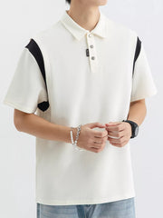 Men's beige cotton polo shirt with contrast black shoulder panels and buttoned placket.