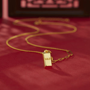 Gold-plated bar pendant necklace with curb link chain and "GOLD" engraving.