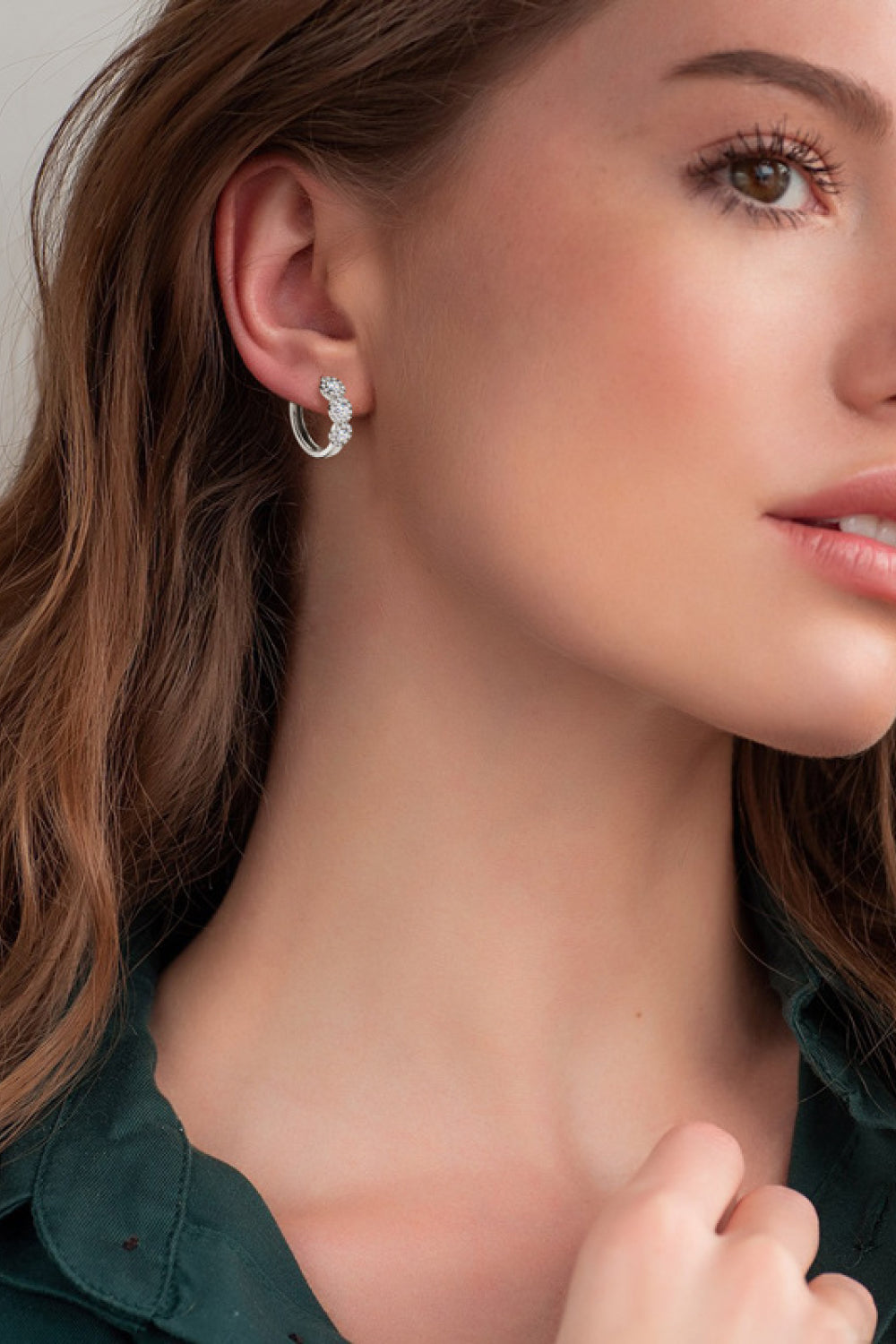 Silver triple cluster diamond huggie hoop earrings with small clear stones.