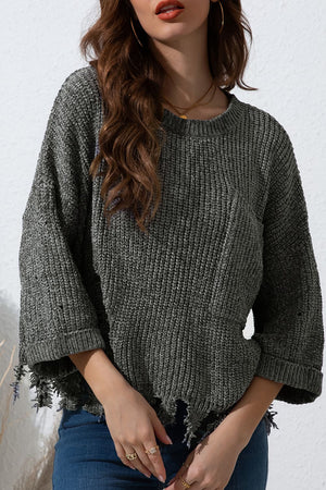 Distressed knit sweater in dark gray with a pocket detail and frayed hem.