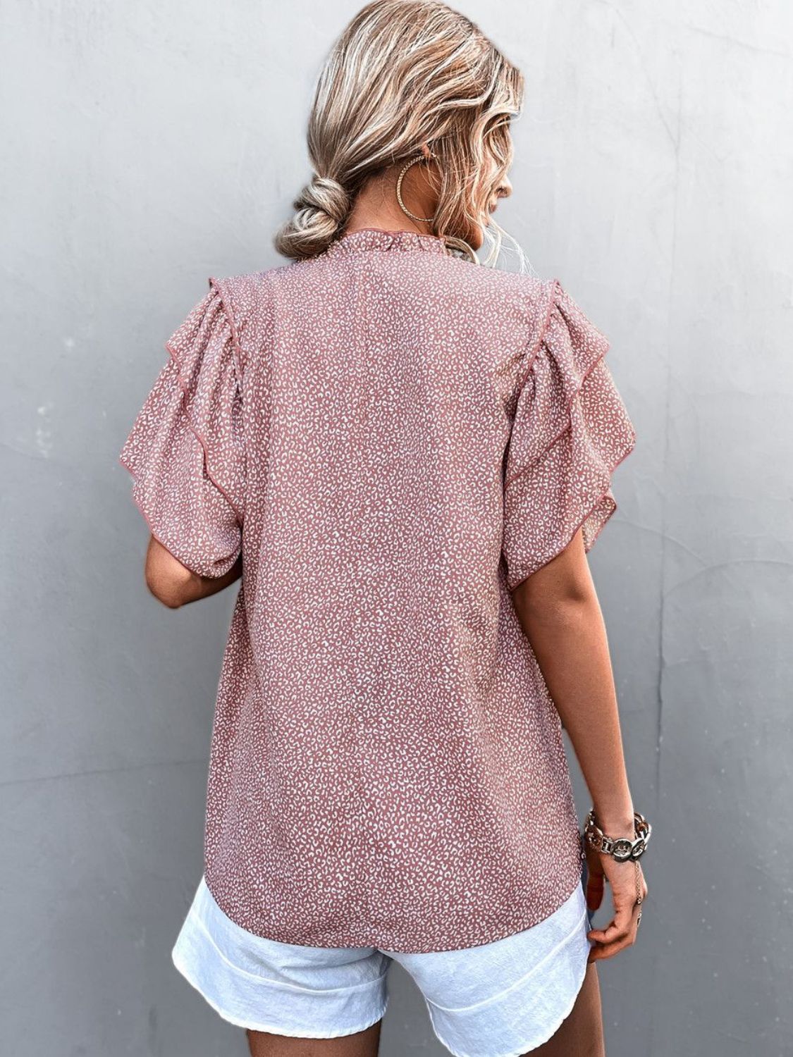 Pink ditsy print blouse with ruffle sleeves and a ruffled neckline.
