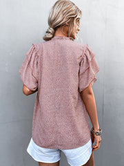 Pink ditsy print blouse with ruffle sleeves and a ruffled neckline.