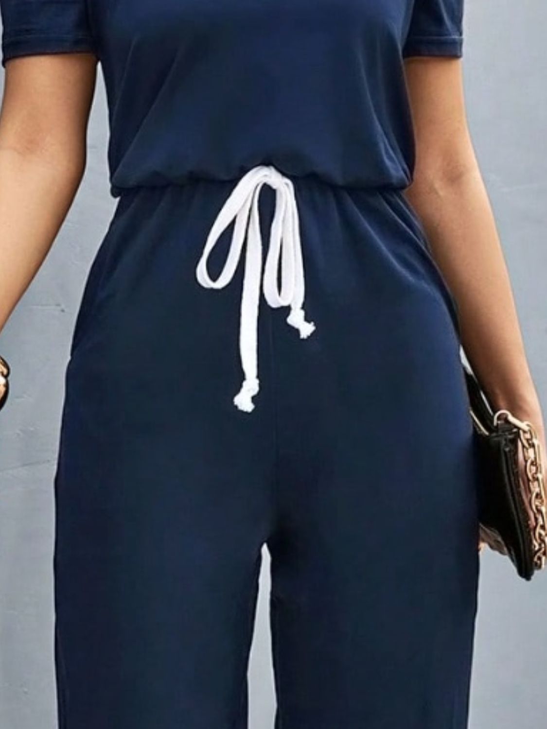 Dark blue jumpsuit with puffed sleeves, drawstring waist, and wide legs.