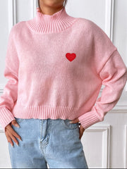 Blush pink cropped turtleneck knit sweater with embroidered red heart detail.
