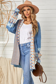 Blue open-front knit cardigan with geometric trim and long sleeves, styled with jeans.