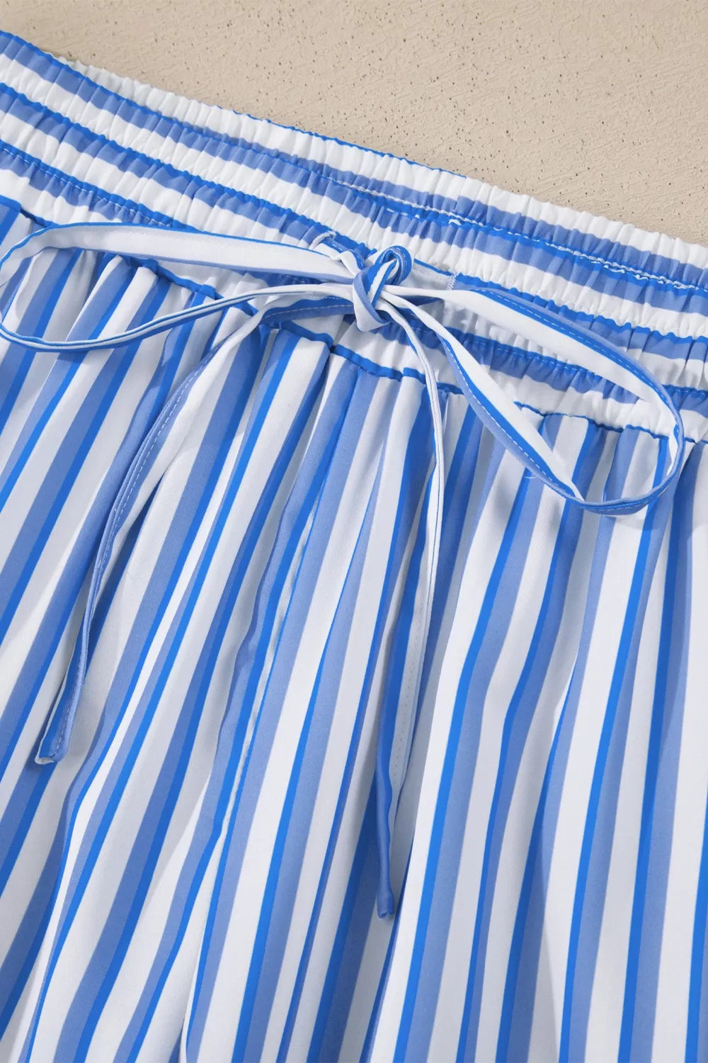Maternity pants with blue and white vertical stripes, elastic waistband, and drawstring tie.