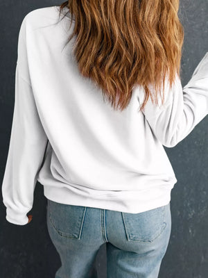 White crewneck sweatshirt with long sleeves, styled with jeans.