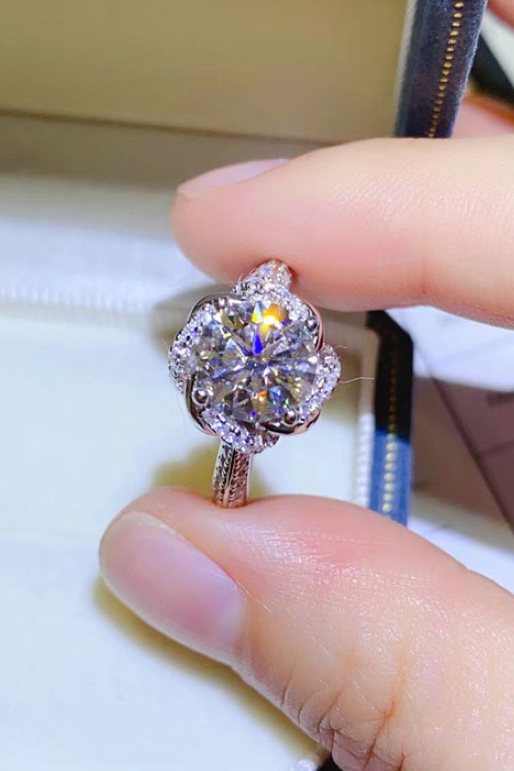 Silver floral halo moissanite engagement ring with a round center stone and pavé band.