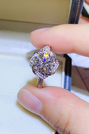 Silver floral halo moissanite engagement ring with a round center stone and pavé band.