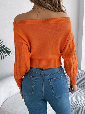 Orange cable knit off-shoulder crop sweater with textured sleeves.