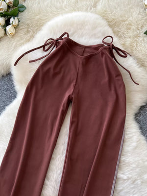 Brown maternity wide-leg pants with tie-waist detail and contrast stitching.