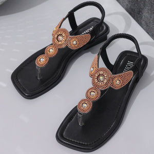 Black t-strap sandals with iridescent beadwork and jeweled embellishments.
