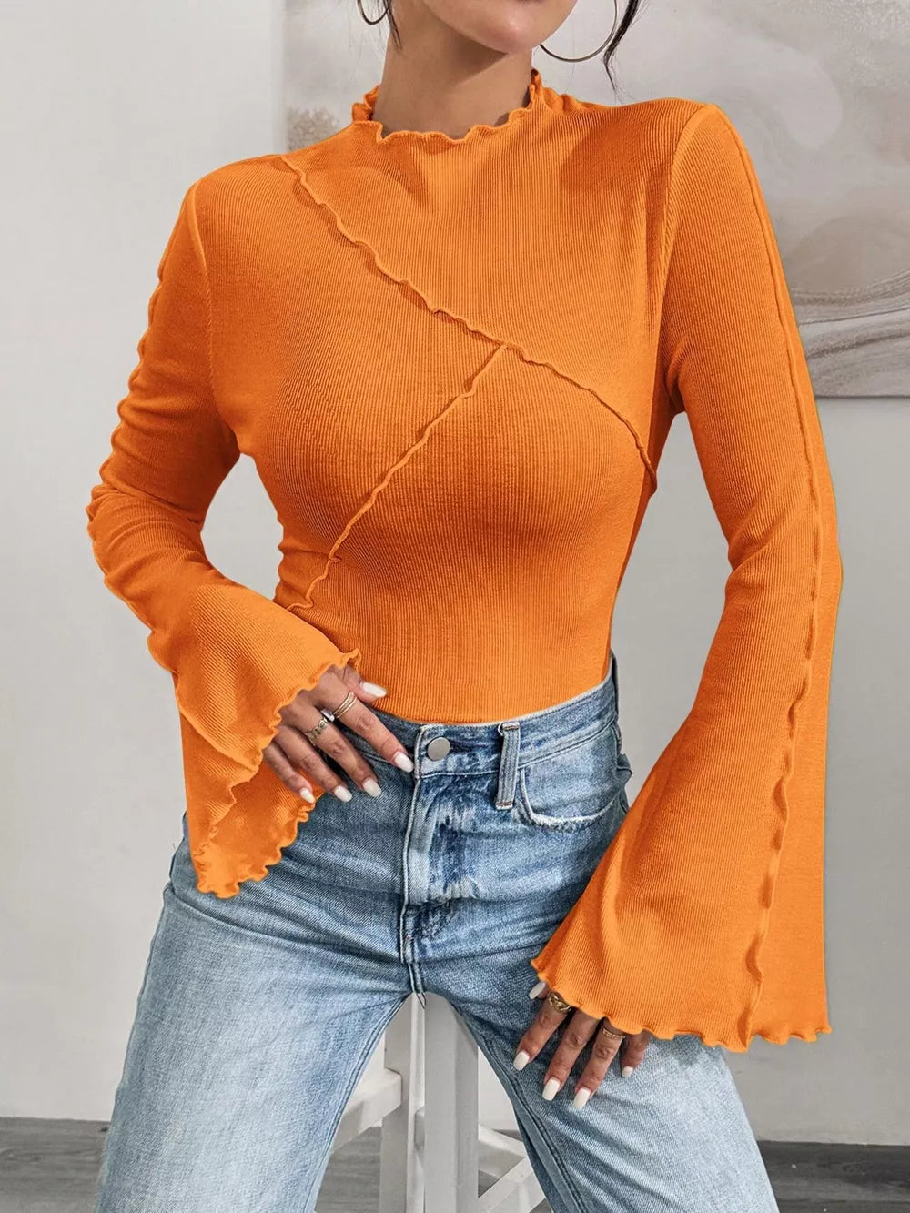Orange lettuce edge flare sleeve t-shirt with seam detail and ruffled neckline.