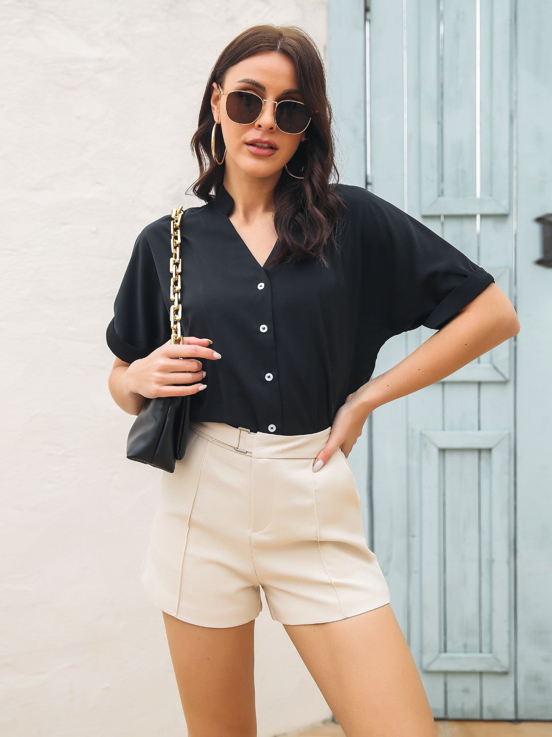 Black short sleeve blouse with notch neckline and button front, cuffed sleeves.