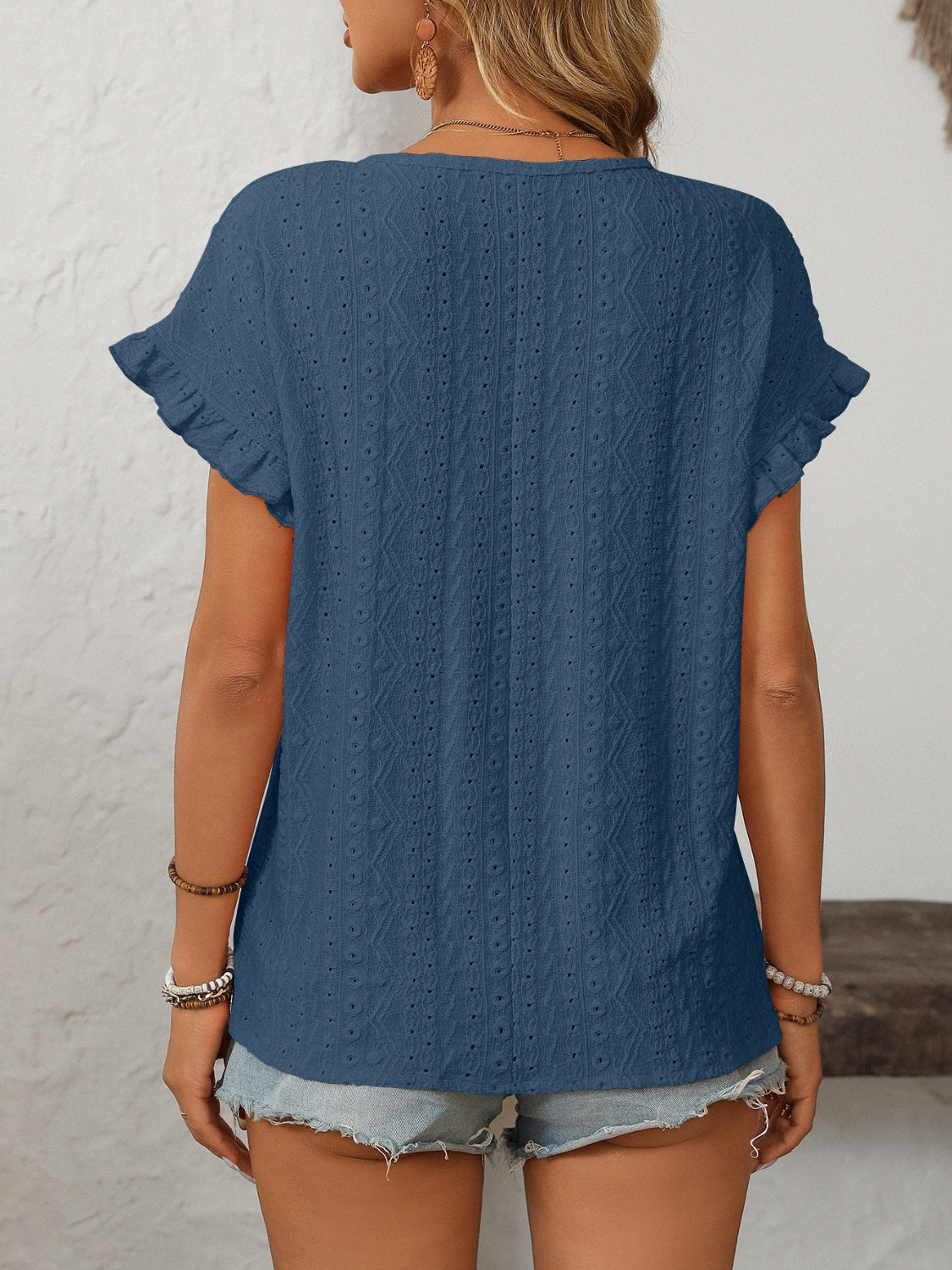 Blue eyelet knit blouse with ruffled short sleeves and a textured pattern.