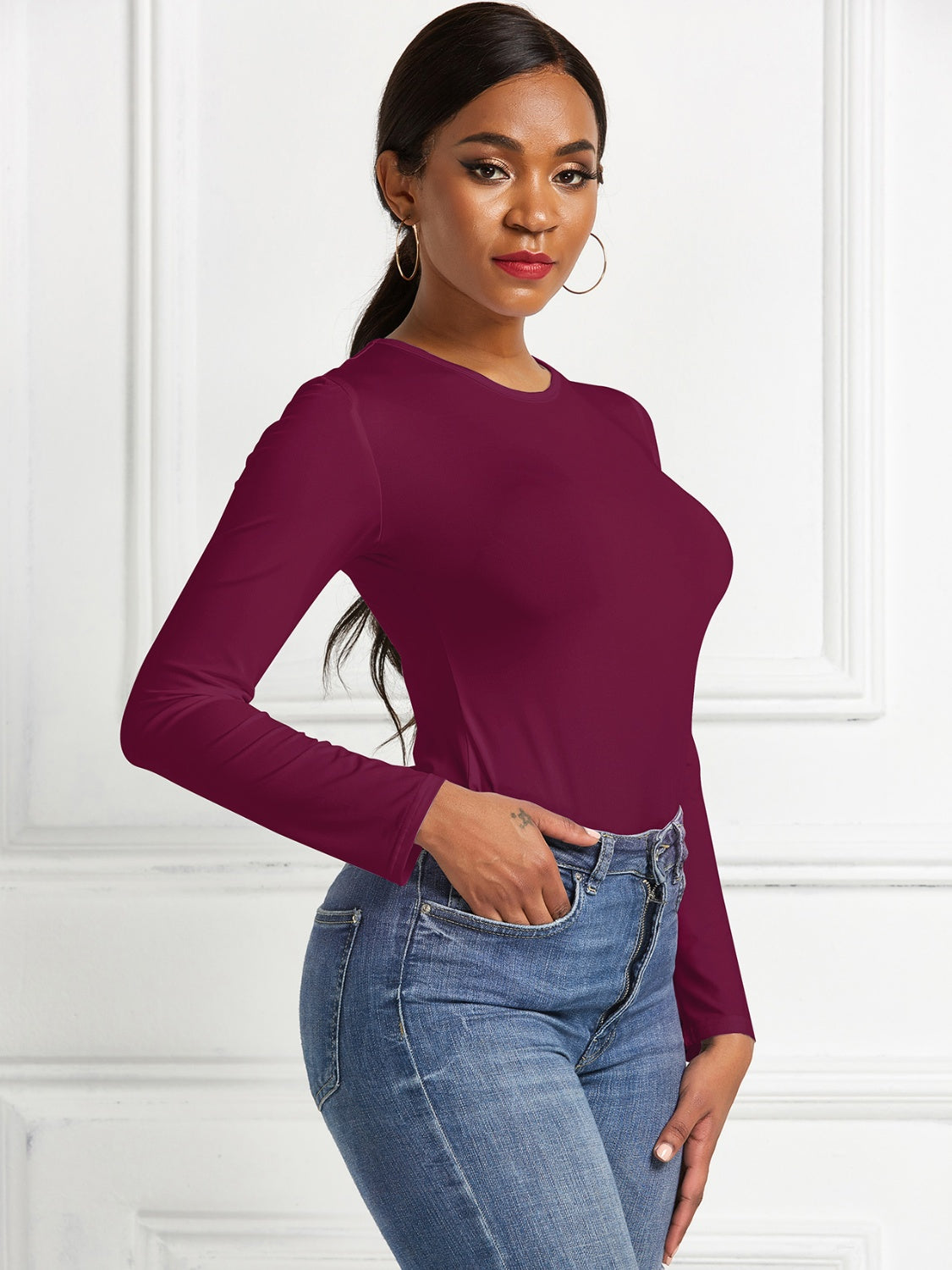Burgundy ribbed jersey bodysuit with long sleeves and crew neck, styled with jeans.