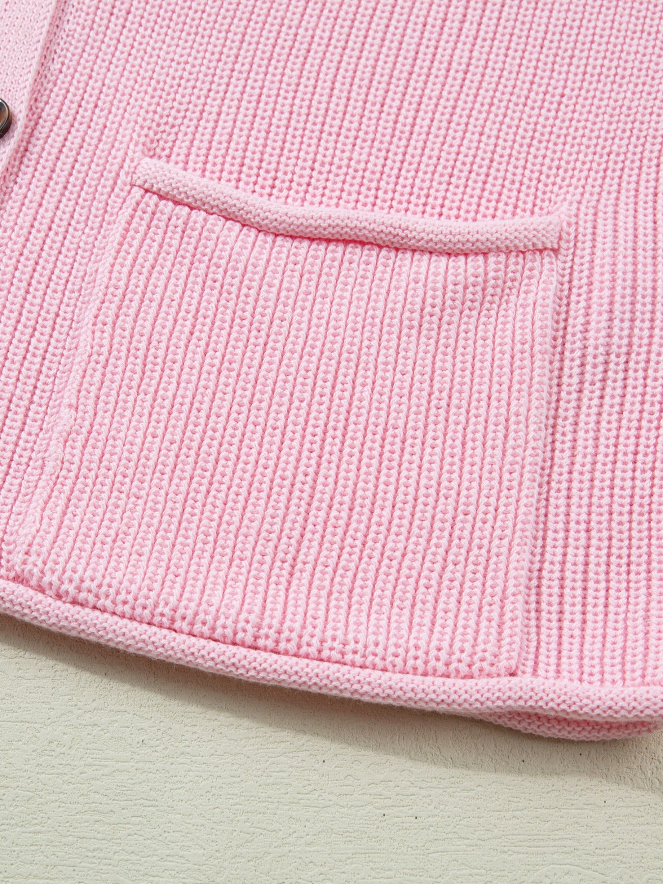 Pink acrylic knit sweater vest with button front and patch pocket detail