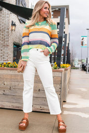 Rainbow crochet openwork sweater with long sleeves and a crew neck, styled with white distressed jeans.