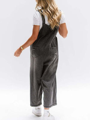 Ripped relaxed fit denim overalls in blue-black with distressed details and wide legs.