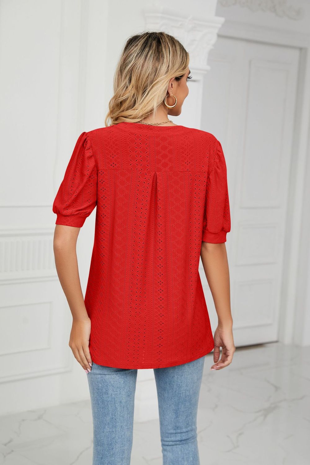 Red perforated puff sleeve blouse with a keyhole neckline and back pleat detail.