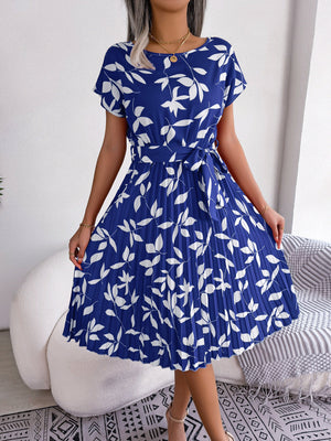 Blue midi dress with white leaf print, short sleeves, belted waist, and pleated skirt.