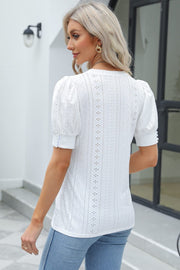 White eyelet puff sleeve blouse with button cuffs and V-neck.