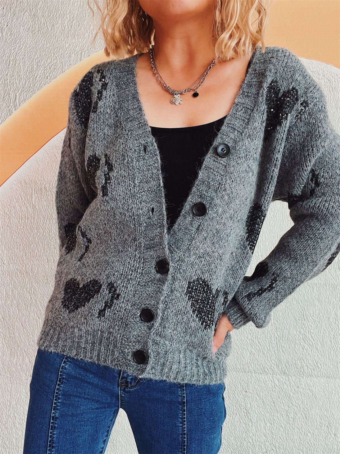 Dark gray knit cardigan with black heart motif, button front, and V-neck.
