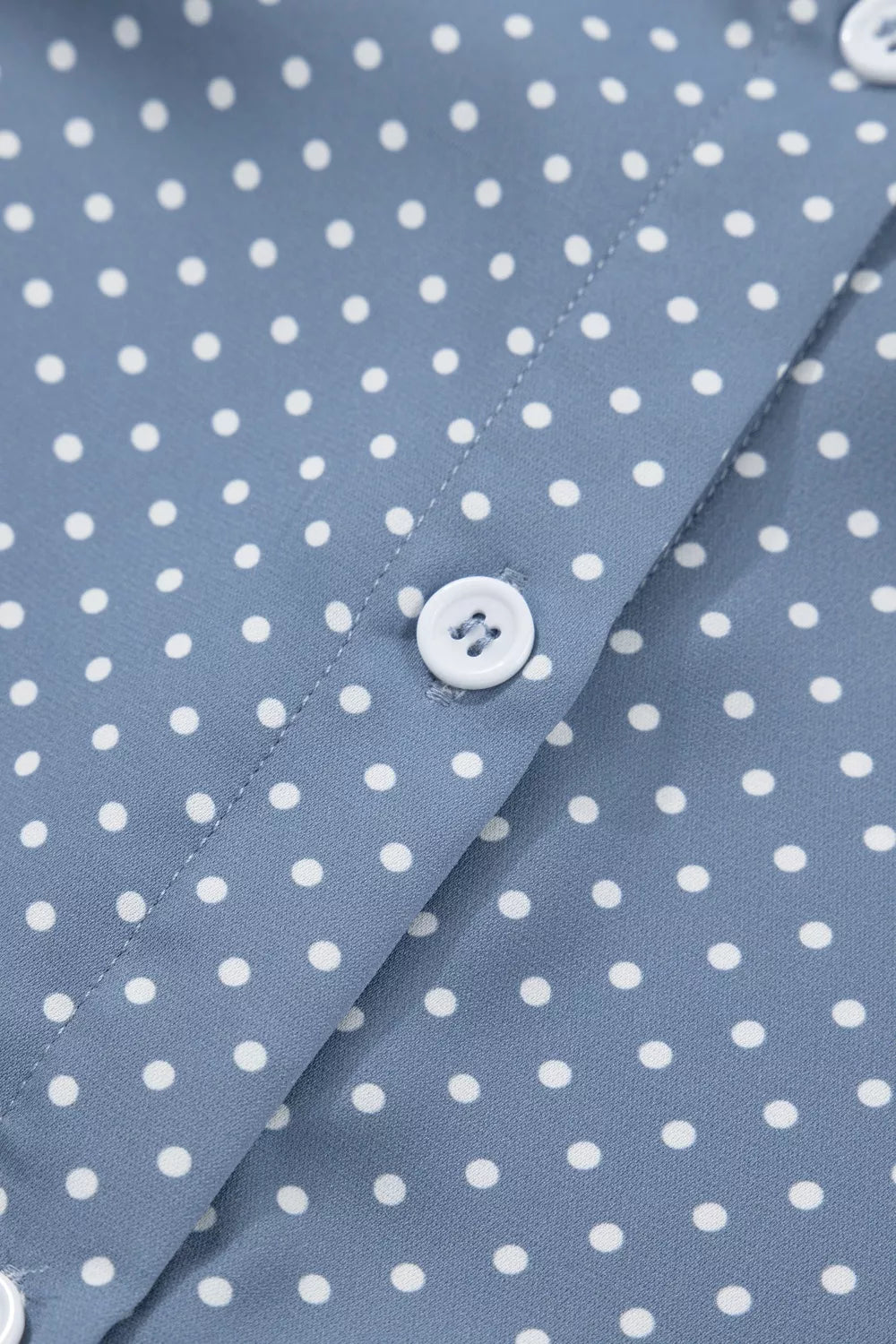 Polyester polka dot shirt with white buttons and cuffed short sleeves.