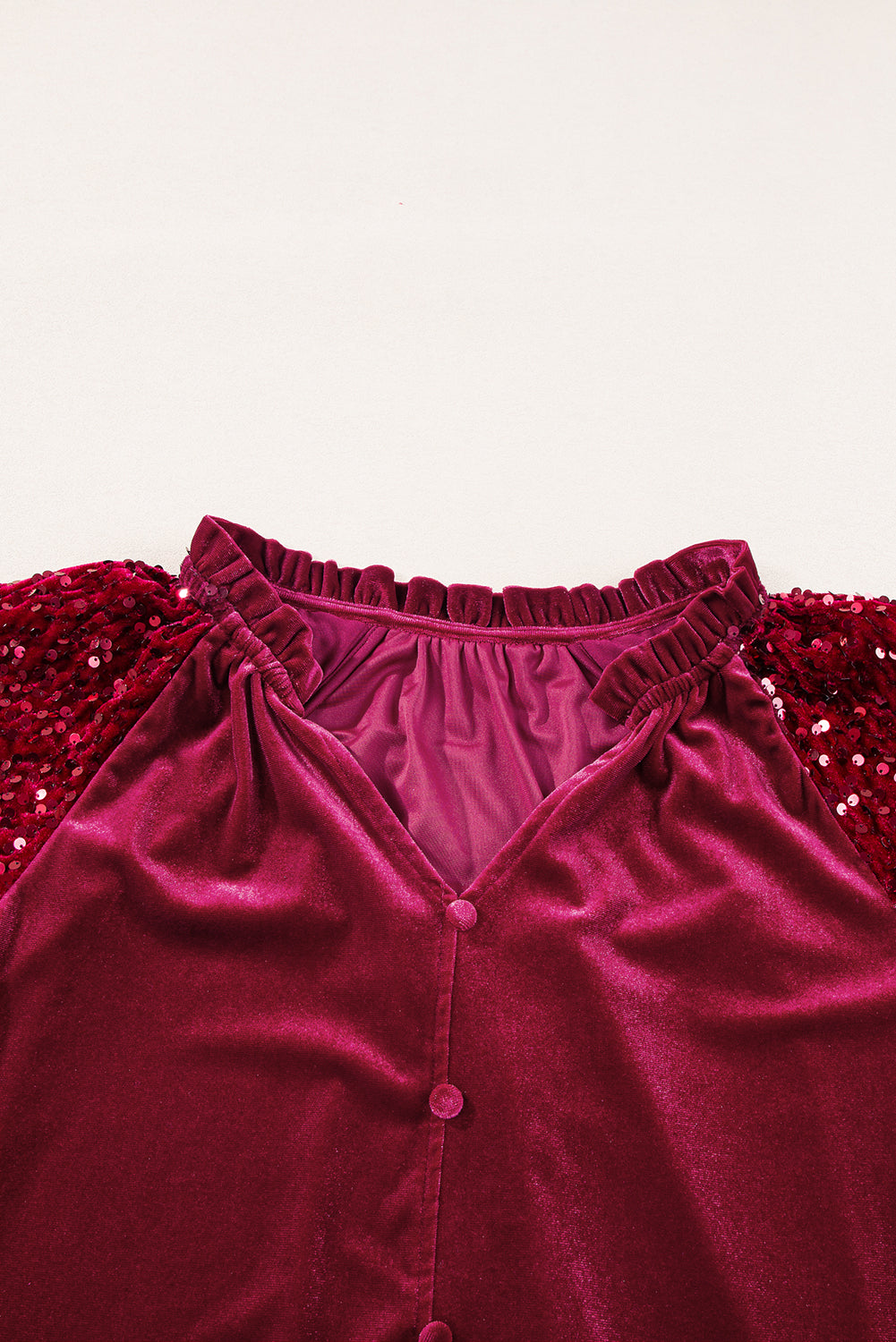 Red velvet blouse with sequin sleeves and ruffled neckline.