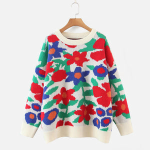 White acrylic crewneck sweater with a bold floral intarsia pattern in red, blue, and green.