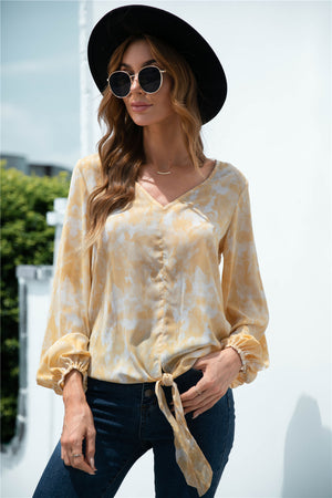 Tie-front blouson top in light yellow with a swirl print, V-neck, and balloon sleeves.