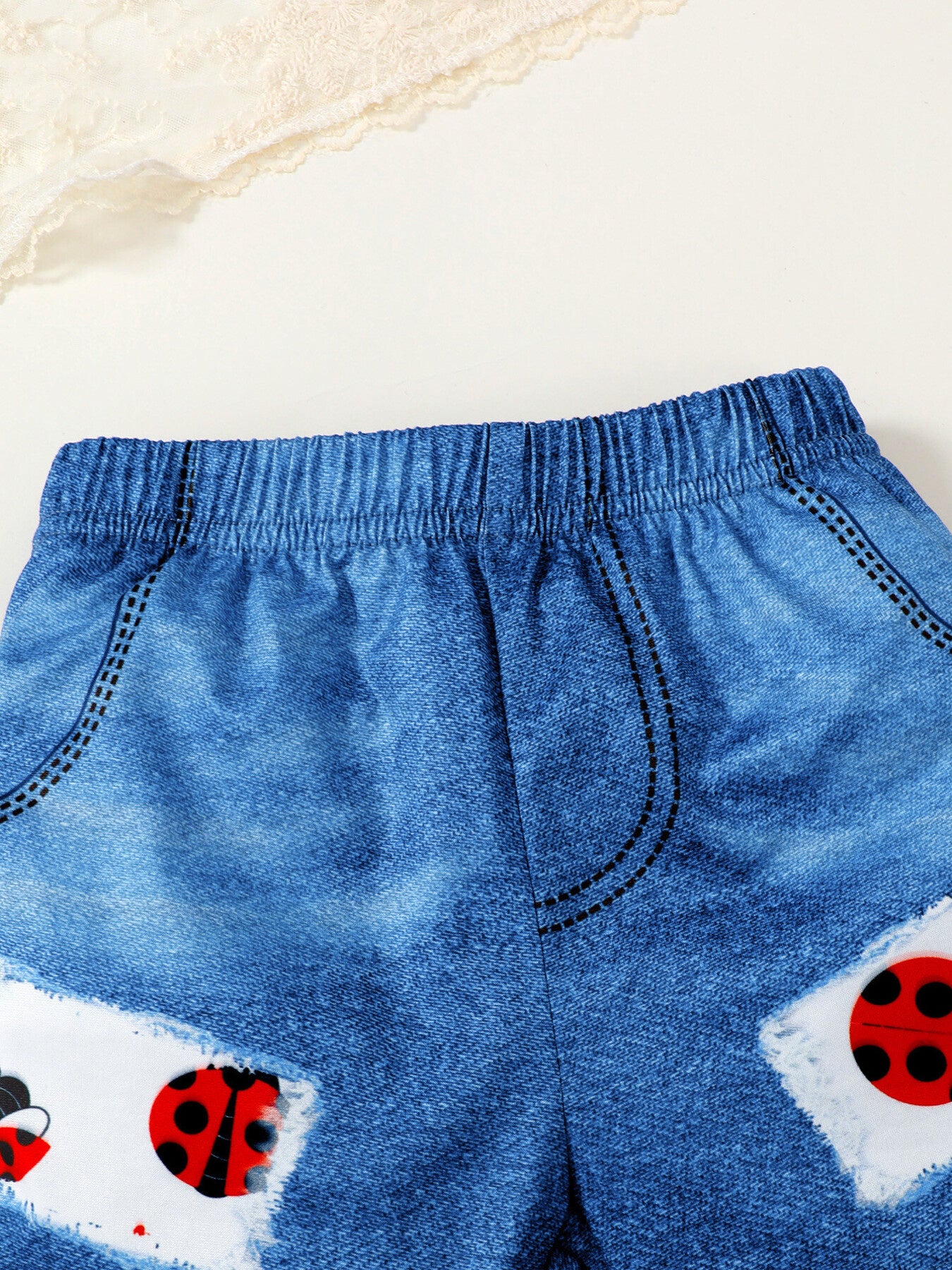 Baby denim-look shorts with ladybug print patches and elastic waistband.