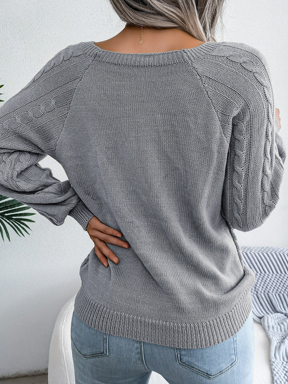 Charcoal cable-knit sweater with buttoned shoulder detail and crew neck.
