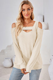 Cream geometric cutout shoulder top with square neckline and long sleeves.