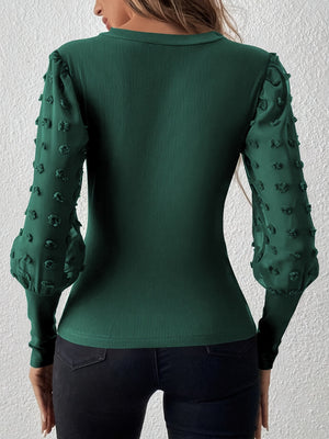 Dark green ribbed bodysuit with sheer pom-pom puff sleeves and fitted cuffs.