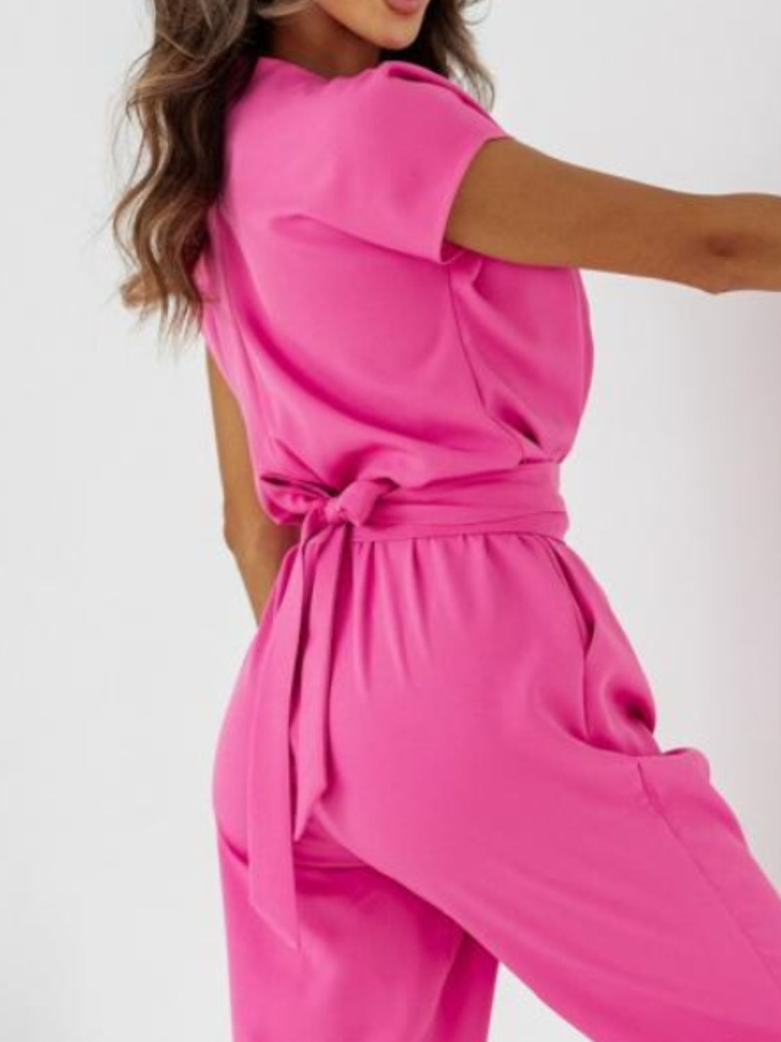 Hot pink wide-leg jumpsuit with short sleeves and a tie waist detail.