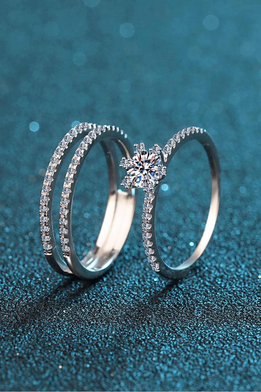 Silver ring trio with clear stones and a central starburst design.