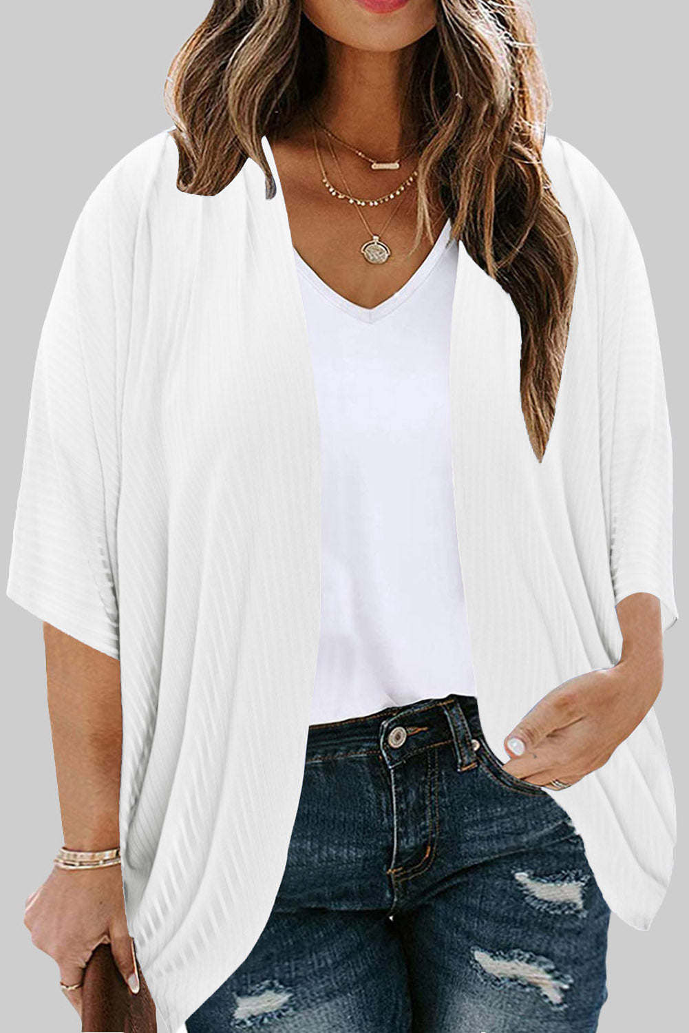 White ribbed batwing cardigan with short sleeves and a drape front, worn over a v-neck top.