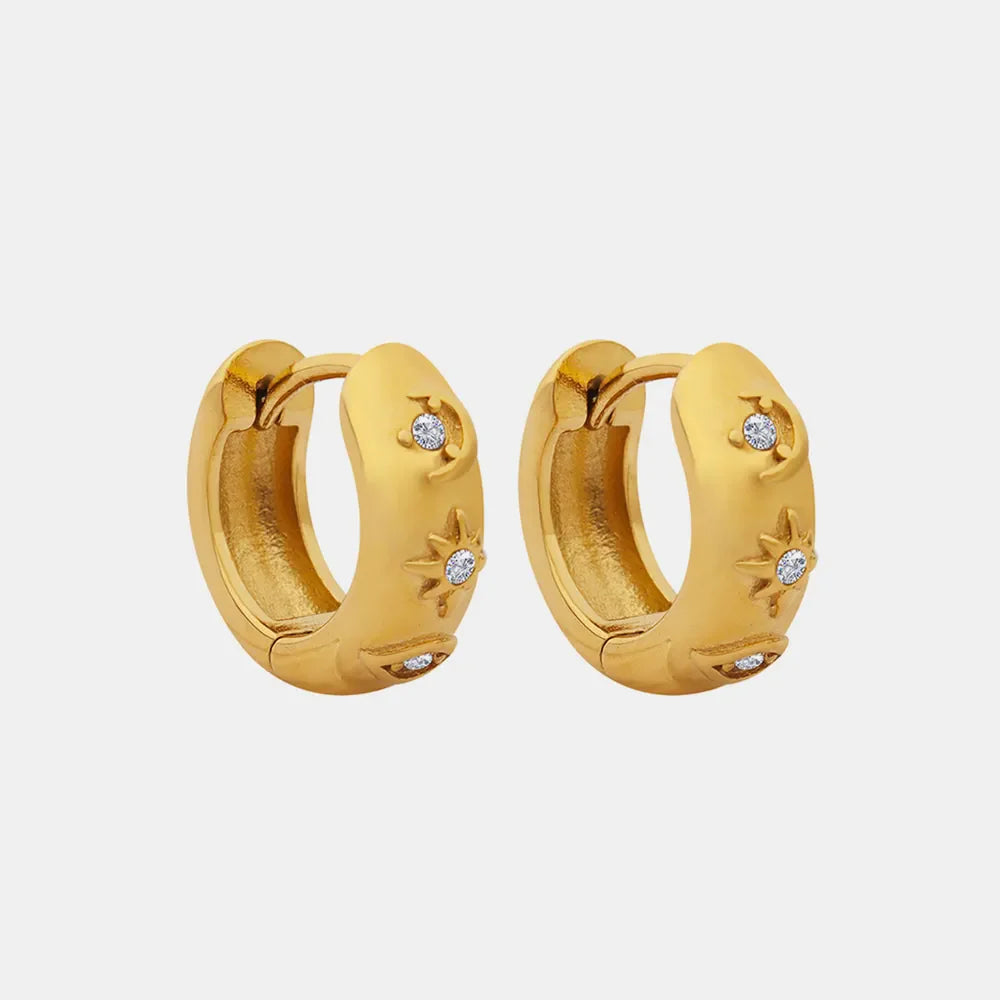 Gold mini huggie hoop earrings with star and moon designs and zirconia embellishments.