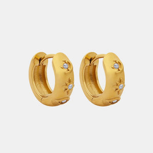 Gold mini huggie hoop earrings with star and moon designs and zirconia embellishments.