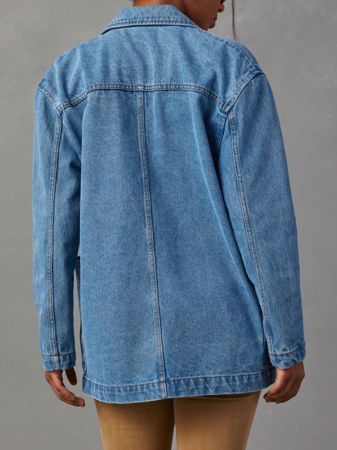 Denim trucker jacket in dusty blue with structured shoulders and buttoned front.