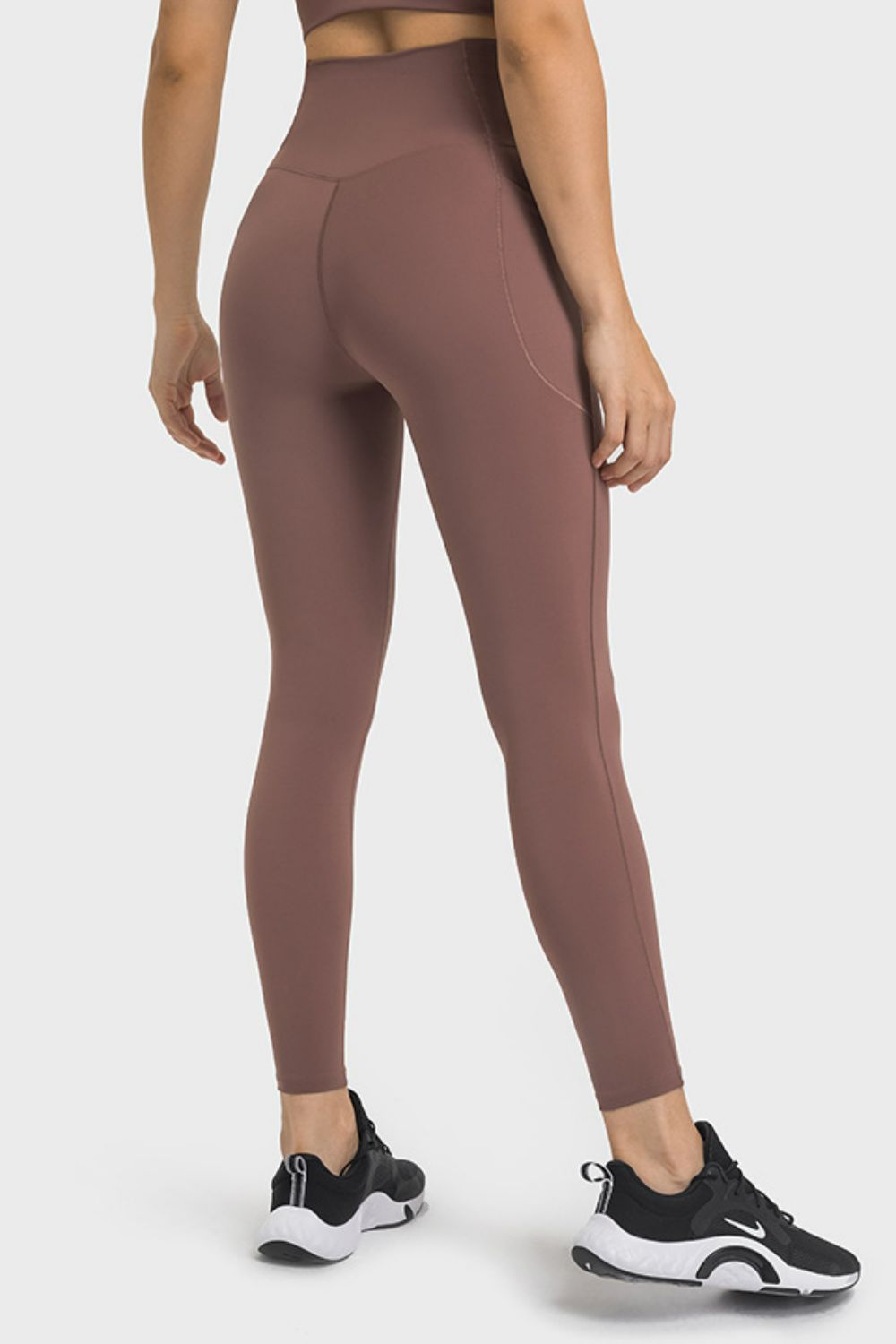 Brown performance leggings with sculpted waistband and side pocket detail.
