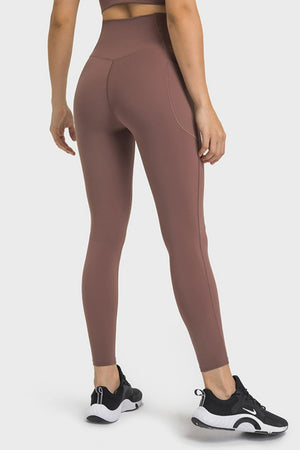 Brown performance leggings with sculpted waistband and side pocket detail.