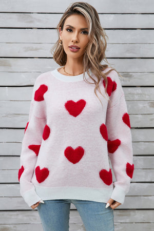 Light pink crewneck sweater with allover red heart appliqué, long sleeves, and ribbed cuffs and hem.